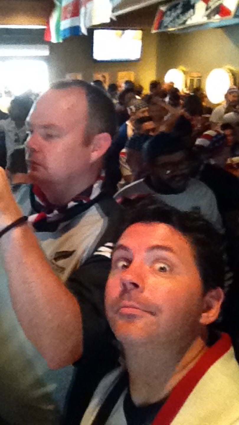 Two guys at a soccer watch party. One making 'wow' eyes at the camera.