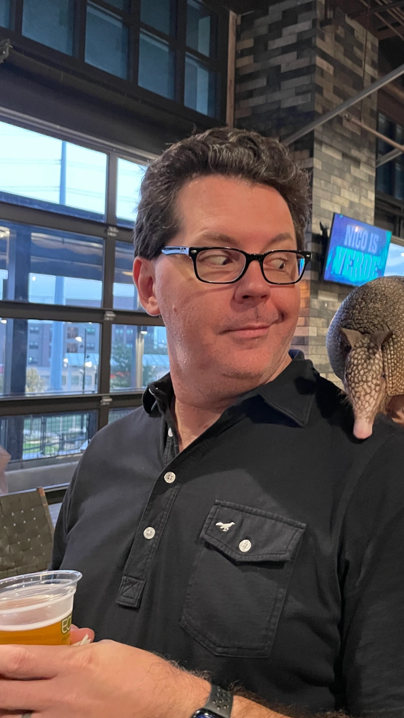 A man with a live armadillo on his shoulder.