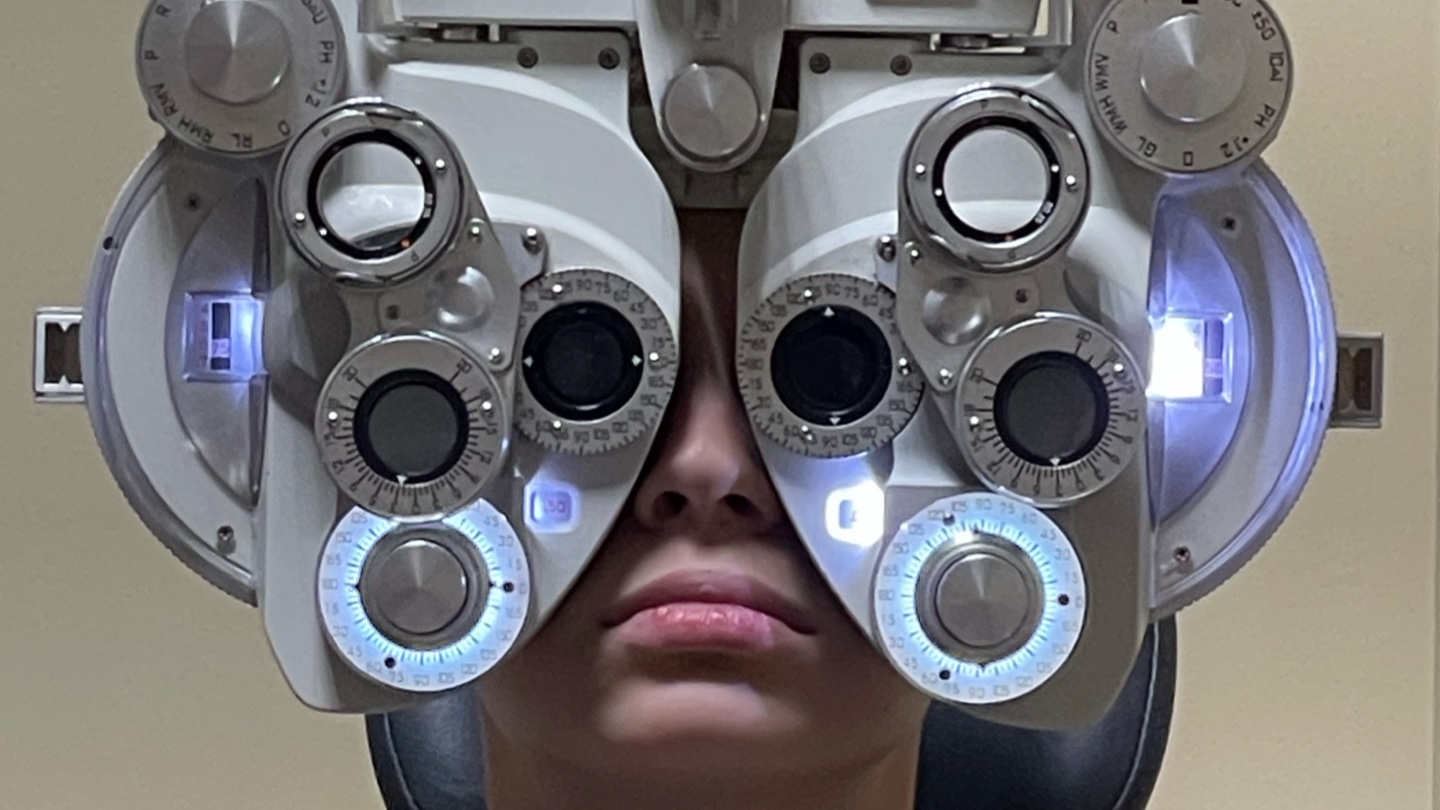 A boy behind a phoropter looking at the camera.